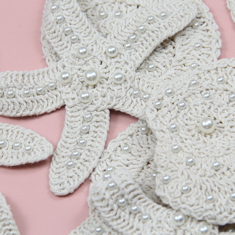 Close-up of cotton thread crochet seashell and starfish appliqué with pearl embellishments