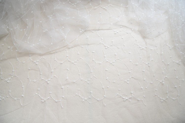 Close-up of ivory embroidered lace fabric with moon design for couture and handmade use