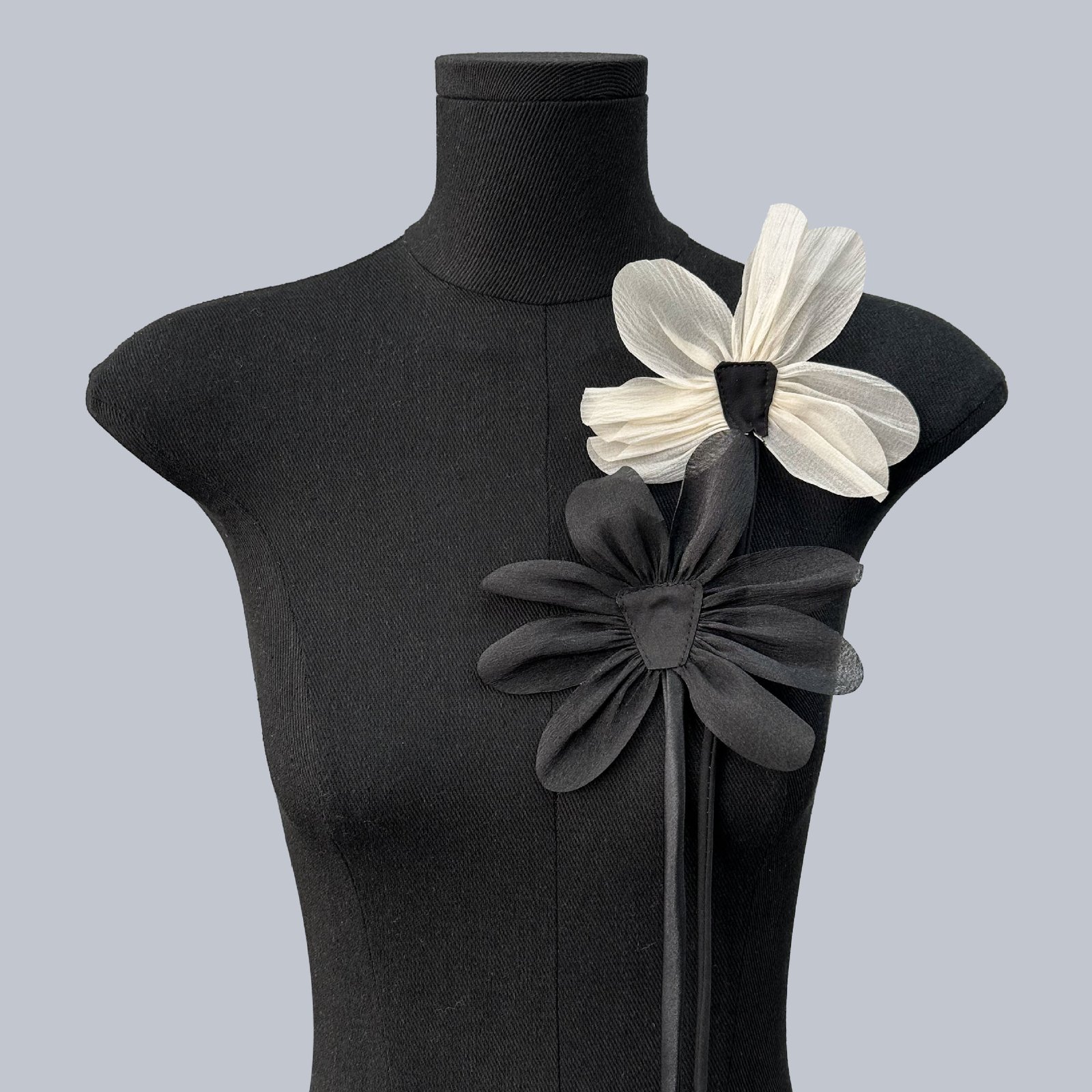 Black and white fabric flower appliqués layered on garment for statement design