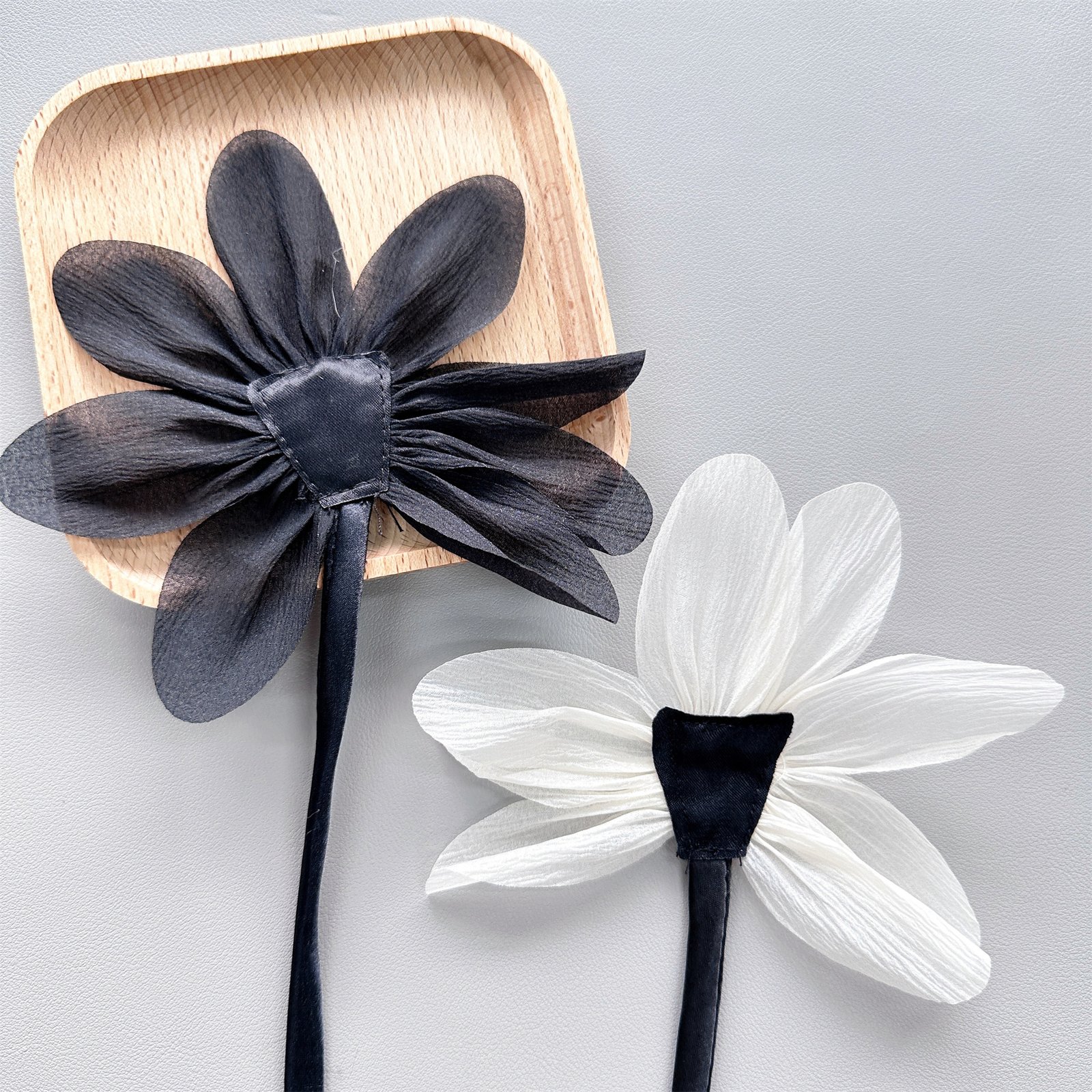 Fabric flower appliqués in black and white displayed as fashion accessories