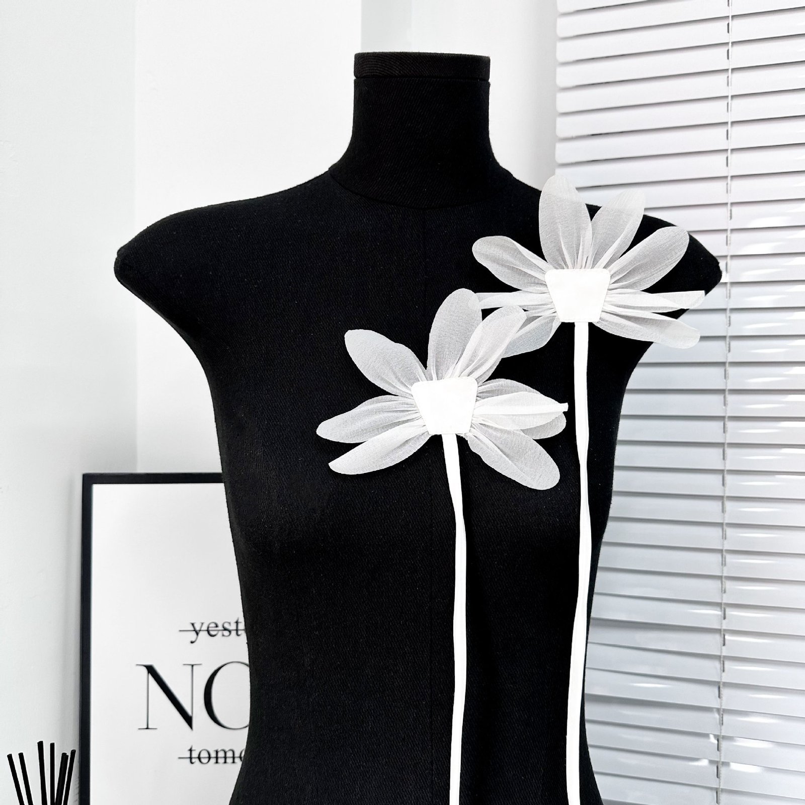 White fabric flower appliqué worn on mannequin as fashion garment embellishment